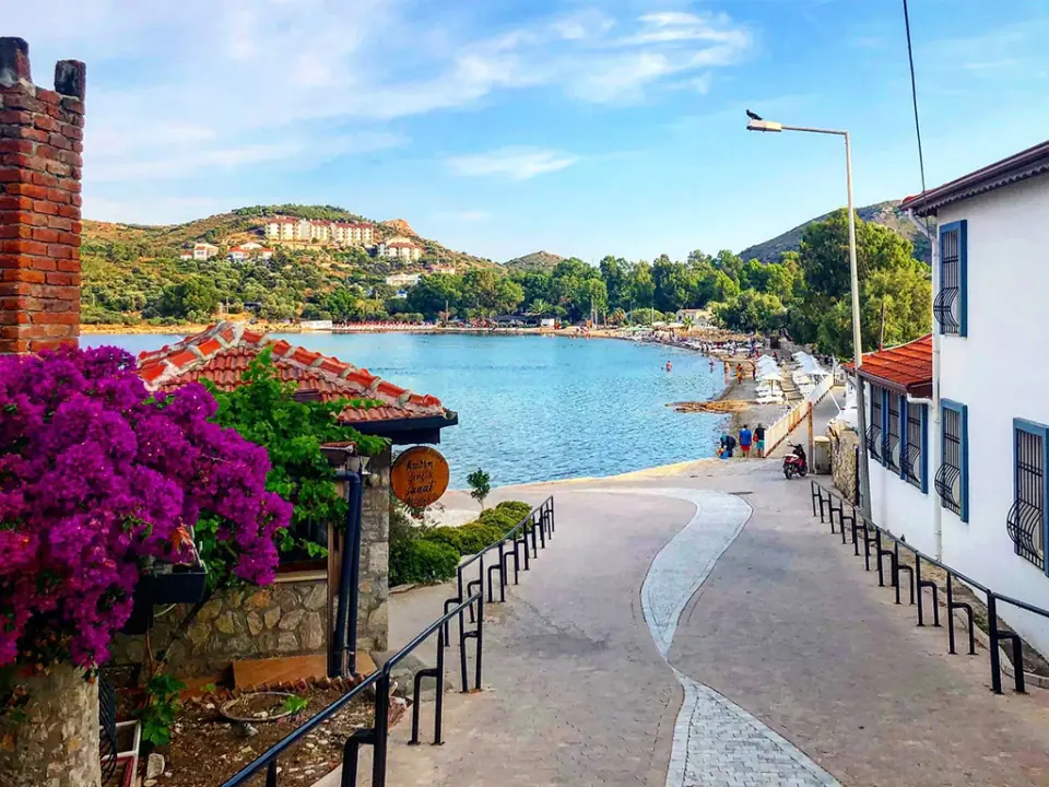 A street in Datça with purple bougainvillea, sloping down to a turquoise bay and beach